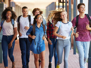 Teens in summer attire walking through a school hall together
