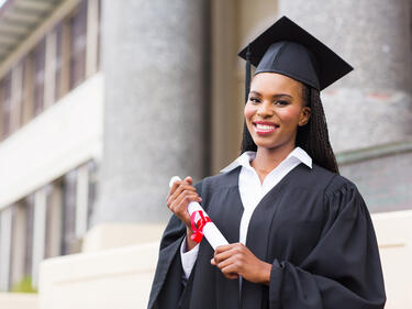 woman in graduation cap and gown holding diploma