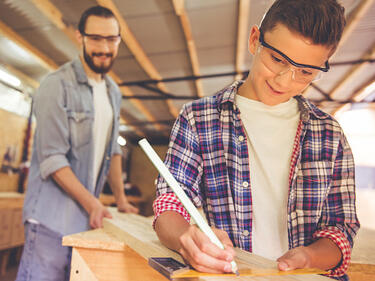 Boy and teacher measuring a board for cutting